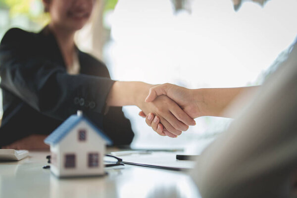Close up Business woman or Real Estate agent shakehand after signing agreement for buying house. Bank manager and real estate concept.