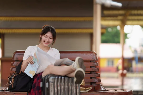 Pretty Young traveler woman looking on maps planning trip at train station. Summer and travel lifestyle concept. — Stockfoto