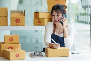 Genç Asyalı serbest yazar reklam için kutu topluyor. KOBİ e ticaret kavramı.