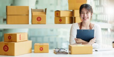 Genç Asyalı serbest yazar reklam için kutu topluyor. KOBİ e ticaret kavramı.