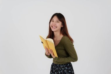 Ayakta duran ve beyaz arka planda izole edilmiş kamerayı gösteren mutlu genç kız görüntüsü.