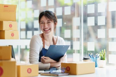 Genç Asyalı serbest yazar reklam için kutu topluyor. KOBİ e ticaret kavramı.