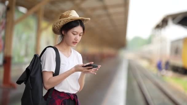 Csinos fiatal utazó nő izgalmas és tervező utazás a vasútállomáson. Nyári és utazási életmód koncepció. — Stock videók