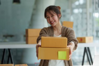 Asyalı küçük işletme sahibi ev ofisinde çalışıyor. Ticari perakende pazarı ve çevrimiçi pazarlama dağıtımı, KOBİ e-ticaret kavramı.