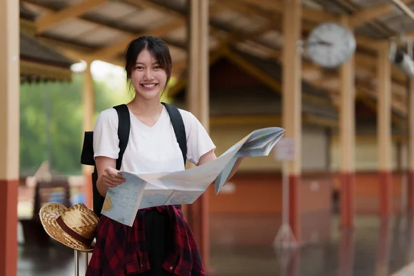 Ung resenär kvinna tittar på kartor planerar resa på tågstationen. Sommar och resor livsstil koncept. — Stockfoto