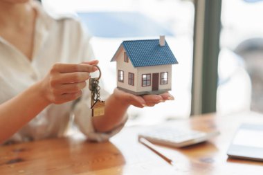 Close up Business woman or Real Estate agent giving house key after signing agreement for buying house. Bank manager and real estate concept.