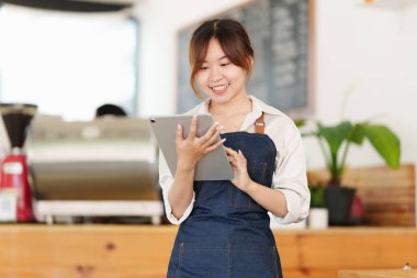 Siparişleri kontrol etmek için tabletli Asyalı barista kafe sahibinin portresi. KOBİ girişimci iş konsepti.