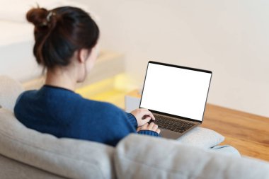 Sosyal medyayı dizüstü bilgisayarla kullanan Asyalı bir kadının portresi. Yaşam tarzı, online alışveriş, kanepede rahatla..