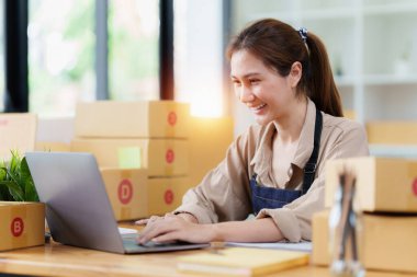 Genç Asyalı serbest yazar, reklam için kutularla dizüstü bilgisayar kullanıyor. KOBİ e ticaret kavramı