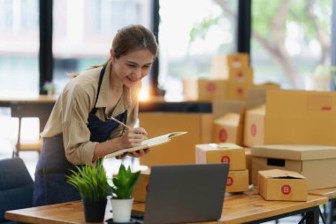 Asyalı bir kadının portresi, e-ticaret çalışanı, müşteriye teslim edilmesi için paket kutusuyla serbest çalışan. Çevrimiçi pazarlama kutu teslimatı kavramı
