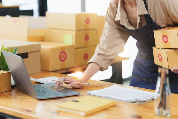 Genç Asyalı serbest yazar, reklam için kutularla dizüstü bilgisayar kullanıyor. KOBİ e ticaret kavramı