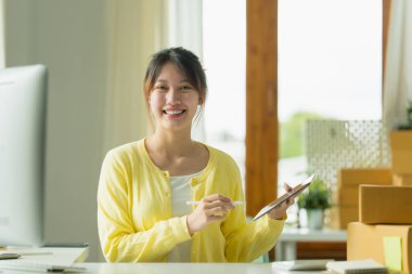 Asyalı küçük işletme sahibi ev ofisinde çalışıyor. Ticari perakende pazarı ve çevrimiçi pazarlama dağıtımı, KOBİ e-ticaret kavramı