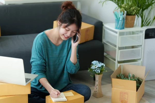 Asyalı küçük işletme sahibi ev ofisinde çalışıyor. Ticari perakende pazarı ve çevrimiçi pazarlama dağıtımı, KOBİ e-ticaret kavramı