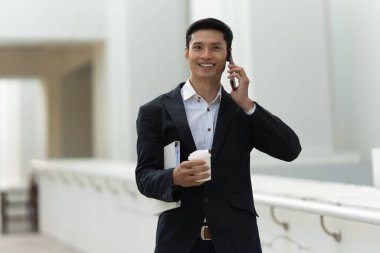 Asyalı iş adamının portresi müşteriyle cep telefonuyla konuşuyor. Hesap ve Finans kavramı