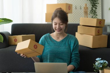 Asyalı küçük işletme sahibi ev ofisinde çalışıyor. Ticari perakende pazarı ve çevrimiçi pazarlama dağıtımı, KOBİ e-ticaret kavramı