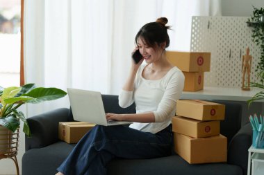 Asyalı küçük işletme sahibi ev ofisinde çalışıyor. Ticari perakende pazarı ve çevrimiçi pazarlama dağıtımı, KOBİ e-ticaret kavramı