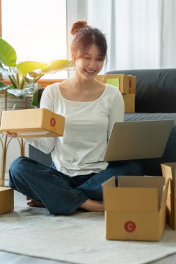 Asyalı küçük işletme sahibi ev ofisinde çalışıyor. Ticari perakende pazarı ve çevrimiçi pazarlama dağıtımı, KOBİ e-ticaret kavramı