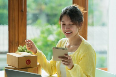 Genç Asyalı serbest yazar reklam için kutu topluyor. KOBİ e ticaret kavramı