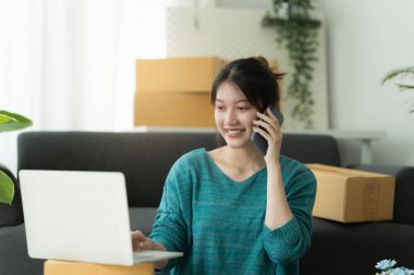 Asyalı küçük işletme sahibi ev ofisinde çalışıyor. Ticari perakende pazarı ve çevrimiçi pazarlama dağıtımı, KOBİ e-ticaret kavramı