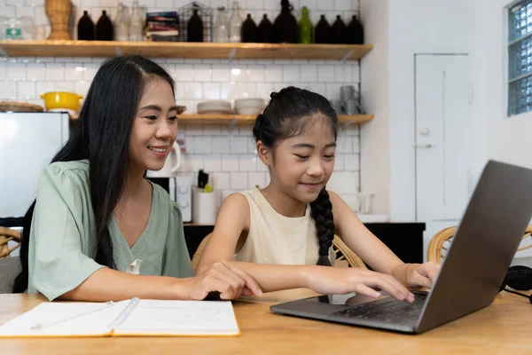 Family and home school concept. Asian mother teach her daughter using application on laptop at home