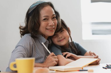 Asyalı kıdemli iş kadını evde çalışırken torununun mutlu anları kucaklaşır. Aile kavramı