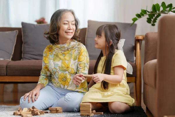 亚洲祖母和孙女一起玩Jenga构造函数的快乐时光 儿童在家中的娱乐活动 — 图库照片