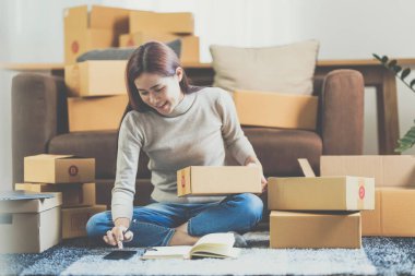 Asyalı küçük işletme sahibi ev ofisinde çalışıyor. Ticari perakende pazarı ve çevrimiçi pazarlama dağıtımı, KOBİ e-ticaret kavramı