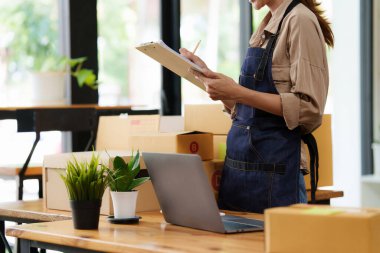 Asyalı küçük işletme sahibi ev ofisinde çalışıyor. Ticari perakende pazarı ve çevrimiçi pazarlama dağıtımı, KOBİ e-ticaret kavramı