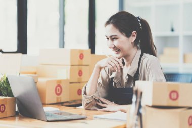 Asyalı küçük işletme sahibi ev ofisinde çalışıyor. Ticari perakende pazarı ve çevrimiçi pazarlama dağıtımı, KOBİ e-ticaret kavramı