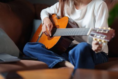 Acemi bir kadın akustik gitar dersi veriyor.