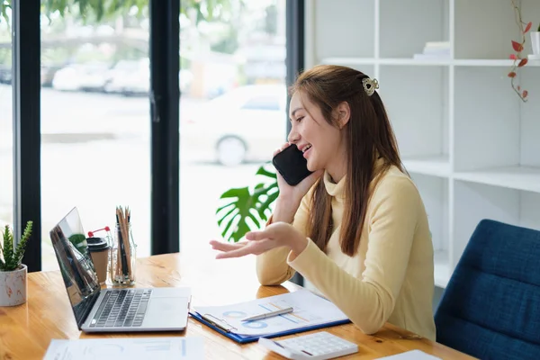 Bilgisayarda çalışan cep telefonu olan genç bir kadın resmi. öğrenim ya da evde online konsept çalışma