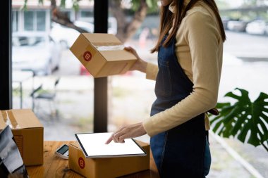 Asyalı küçük işletme sahibi ev ofisinde çalışıyor. Ticari perakende pazarı ve çevrimiçi pazarlama dağıtımı, KOBİ e-ticaret kavramı