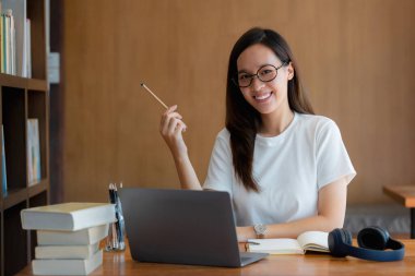 Laptop bilgisayarında çalışan kulaklıklı genç bir kadının görüntüsü. öğrenim ya da evde online konsept çalışma