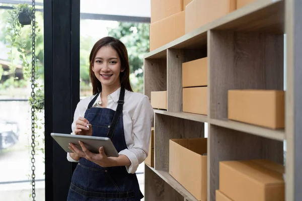 Attractive Asian entrepreneur business woman checking order by tablet.