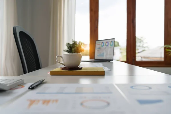 Cup of coffee and finance paperwork on white desk at office