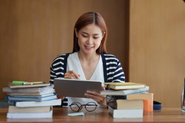 Back to school concept. Young college woman reading book at library.