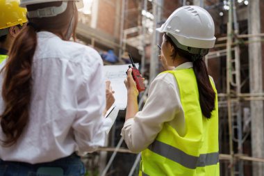 Structural engineer and architect discussing and working with blueprints at the outdoors construction site.