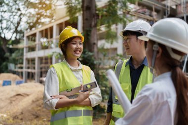 Structural engineer and architect discussing and working with blueprints at the outdoors construction site.