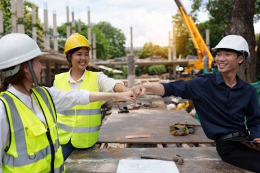 Structural engineer and architect discussing and working with blueprints at the outdoors construction site.