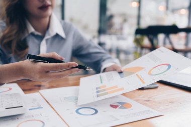 Asyalı İş kadını, cep telefonuyla konuşan iş ekibiyle teknik fiyat grafiğini ve göstergeyi analiz etmeye çalışıyor. Hesap ya da tasarruf parası ya da sigorta kavramı.