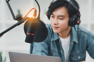 Asian podcaster making audio podcast working at home studio. selective focus.
