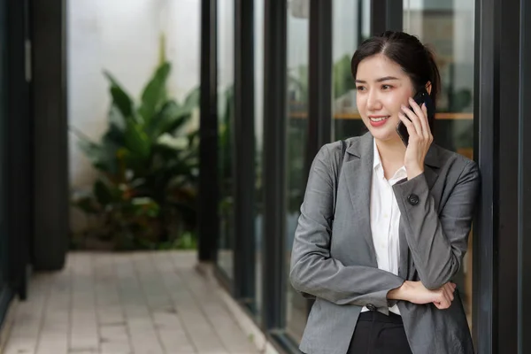 Νεαρή Ασιάτισσα Επιχειρηματίας Χαμογελά Και Μιλάει Στο Κινητό Τηλέφωνο Στέκεται — Φωτογραφία Αρχείου