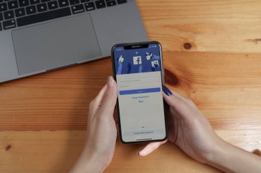 CHIANGMAI, THAILAND - AUG 26, 2022 : Asian woman holds smartphone with facebook login screen. facebook from meta.