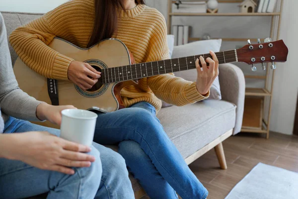 A beginner woman with best friend playing acoustic guitar lesson.