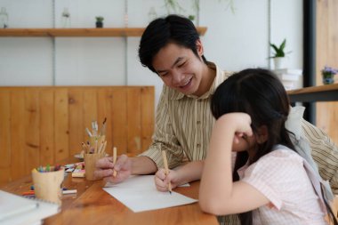 A happy kid and father painting at home. Handmade skills training.