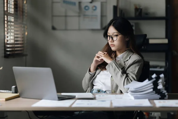 Stressed Asian business woman worry with many document on desk at office.