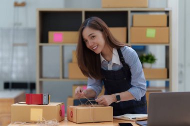 Asyalı küçük işletme sahibi ev ofisinde çalışıyor. Ticari perakende pazarı ve çevrimiçi pazarlama dağıtımı, KOBİ e-ticaret kavramı.