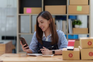 Asyalı küçük işletme sahibi ev ofisinde çalışıyor. Ticari perakende pazarı ve çevrimiçi pazarlama dağıtımı, KOBİ e-ticaret kavramı.