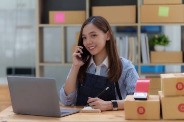 Asyalı küçük işletme sahibi ev ofisinde çalışıyor. Ticari perakende pazarı ve çevrimiçi pazarlama dağıtımı, KOBİ e-ticaret kavramı.