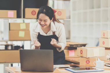 Asyalı küçük işletme sahibi ev ofisinde çalışıyor. Ticari perakende pazarı ve çevrimiçi pazarlama dağıtımı, KOBİ e-ticaret kavramı.